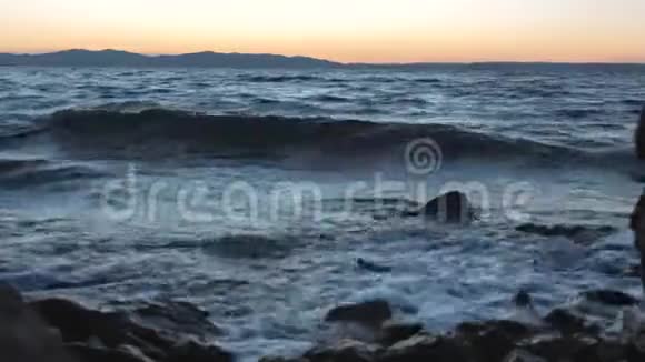 夕阳下海浪拍打着海岸上的岩石视频的预览图