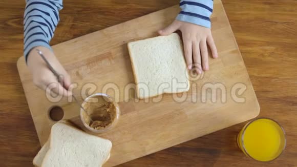 在厨房里用花生酱做三明治的男孩视频的预览图