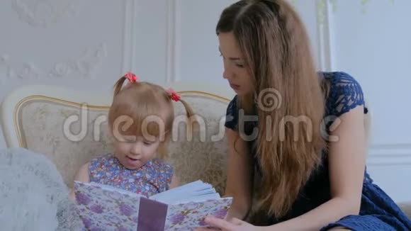 年轻的母亲和她的小女儿正在看照片视频的预览图