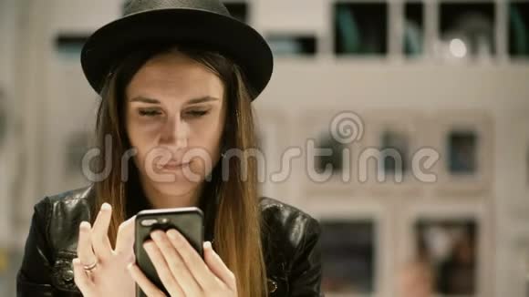 年轻时尚的女人坐在画廊里使用智能手机学生女性独自度过闲暇时间视频的预览图