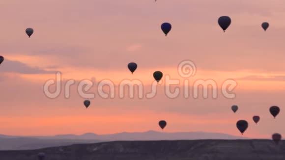 许多热气球飞过土耳其戈尔梅的山谷粉红色的黎明在难以置信的地方视频的预览图