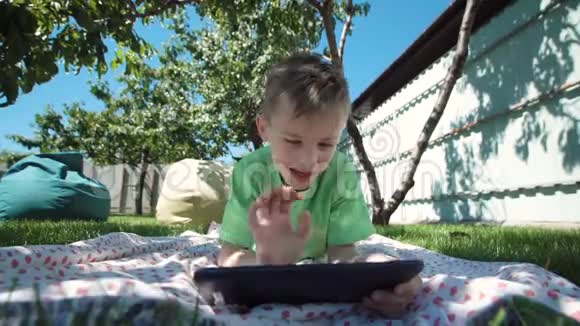 男孩在花园里和平板电脑交流视频的预览图