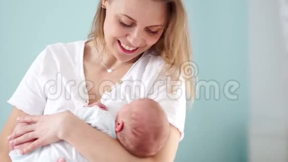 母亲轻轻地抱着一个新生婴儿母爱和关怀安抚和抚摸婴儿的头母亲节视频的预览图
