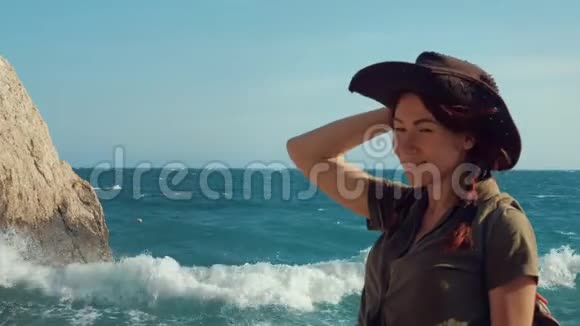 一个美丽的红发旅行女孩戴着牛仔帽在海边的肖像视频的预览图