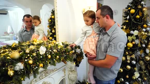 幸福的父亲和可爱的女儿在客厅优雅的圣诞树背景上的节日装饰视频的预览图