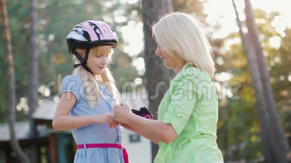 父母照顾妈妈给女儿穿上自行车或溜冰鞋用的肘垫视频的预览图