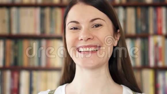 女大学生在图书馆微笑上学的第一天背景书架视频的预览图