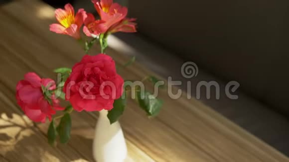 一束可爱的玫瑰和自由的花以及桌上的影子被阳光透过窗帘照亮视频的预览图