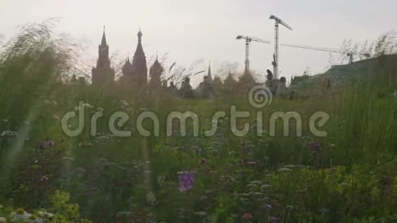晚上人们与克里姆林宫一起坐在草地上在背景上搭建起重机视频的预览图