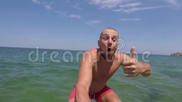 自拍男人用相机从岩石上跳进水里拇指向上高清慢镜头视频的预览图
