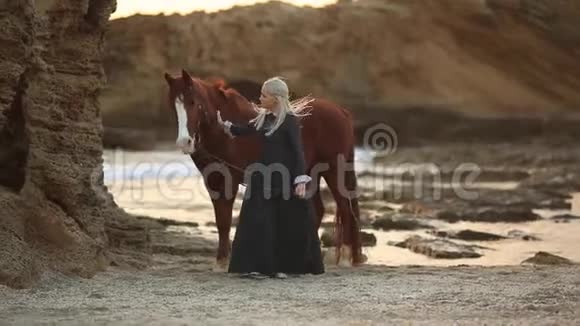 在日落时分女士带着19世纪的历史服装在海滨骑马视频的预览图