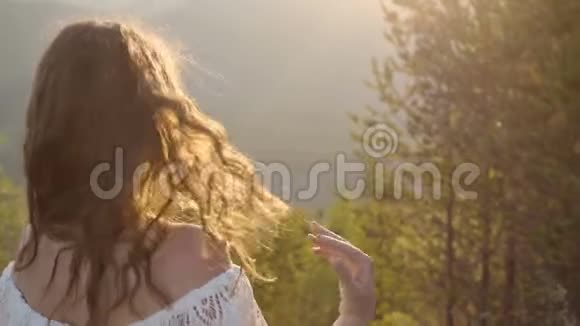 日落时分年轻美丽时尚快乐的微笑女孩站在壮丽的山谷和山丘上视频的预览图