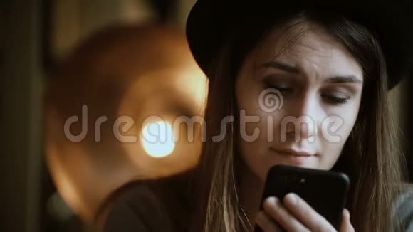 一位年轻的黑发女人拿着智能手机坐在咖啡馆里在触摸屏上输入信息视频的预览图