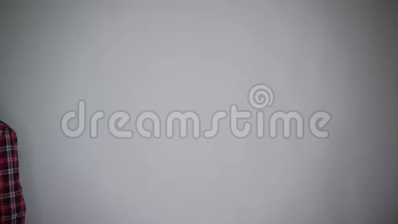 年轻的美女穿着休闲装微笑着拿着油漆滚筒用灰色背景隔离墙画视频的预览图