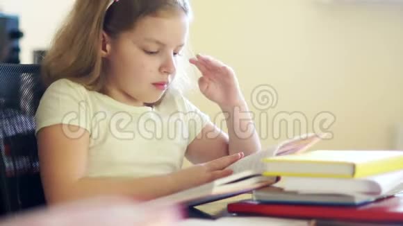 悲伤的女孩坐在桌子旁拿着一堆书她揉着眼睛想睡觉学校教育问题视频的预览图