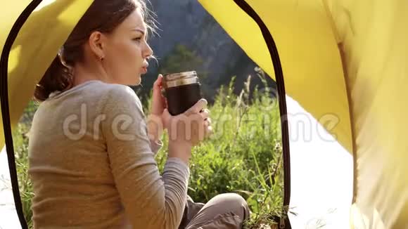 女孩正在山上喝一杯热水瓶里的茶视频的预览图