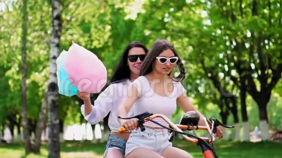 穿着短短裤穿着甜棉的女孩在公园里骑电动滑板车视频的预览图