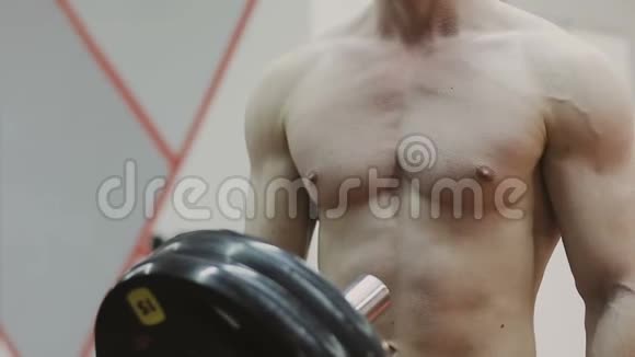 决心肌肉发达的男人把沉重的盘子放在杠铃上在健身房里起来视频的预览图