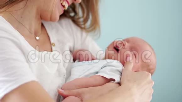 那个女人小心翼翼地把熟睡的新生婴儿抱在怀里她用手指抚摸他的脸开心地笑着视频的预览图