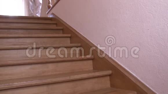 特写一个穿着白色裤子的男人走在房子的一楼的木阶上视频的预览图