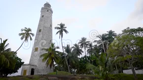 一座石灯塔位于绿色棕榈树和一栋建筑管理员的小房子之间视频的预览图