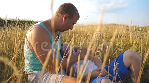 快乐的年轻人躺在草地上和他的小男孩玩耍快乐的爸爸和他的孩子玩得开心视频的预览图