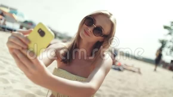 穿比基尼的漂亮女人坐在海滩上自拍视频的预览图