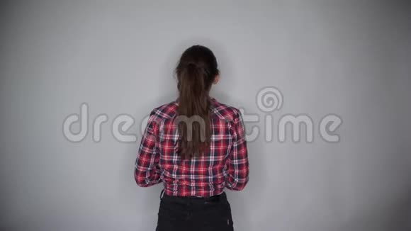 年轻的美女穿着休闲装微笑着拿着油漆滚筒用灰色背景隔离墙画视频的预览图