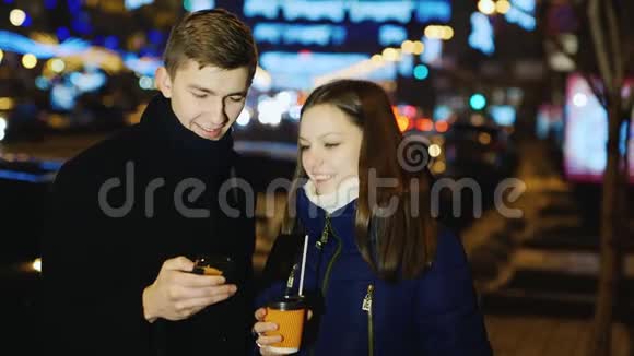 年轻人和女人在一条晚上的街道上说话看手机屏幕视频的预览图