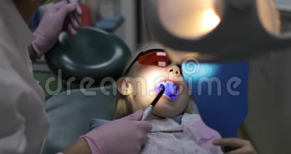 一个小女孩张开嘴坐在牙科椅上视频的预览图