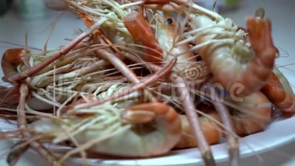 一家海鲜店里的人把煮好的虾放在盘子里拍摄特写视频的预览图