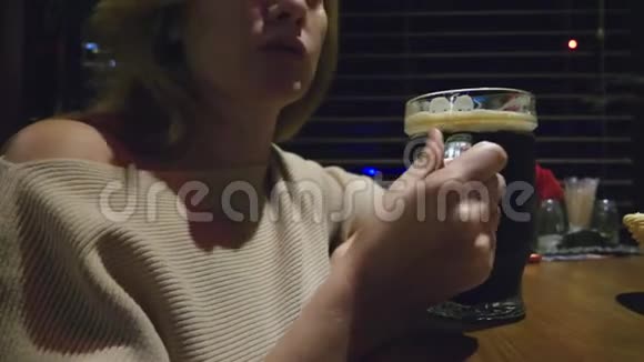一个女人在夜总会喝着一杯黑啤酒视频的预览图