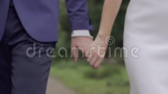 新婚夫妇手指上戴着戒指手牵着手向前走视频的预览图