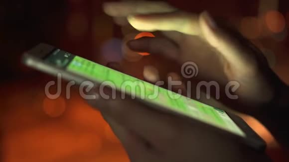 夜间在城市户外使用智能手机触摸屏的女性手部特写浏览信使视频的预览图