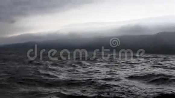 天空中灰色云层和贝加尔湖黑色暗水背景下的风暴视频的预览图