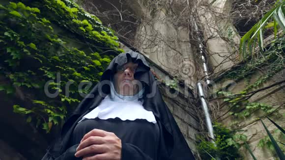 一个修女的鬼魂走过一座古老修道院的废墟4k慢镜头拍摄视频的预览图