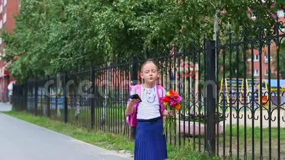 小女孩站在学校附近用手机说话然后走开了回到学校的概念夏日户外手持视频的预览图
