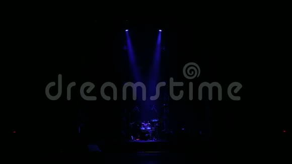 蓝色的聚光灯照亮了黑暗中空荡荡的舞台上的鼓视频的预览图