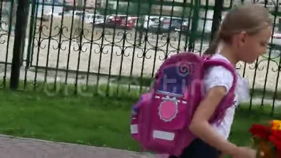 快乐的年轻女孩带着粉红色的背包和一束鲜花回到学校晴天户外手持拍摄女孩视频的预览图