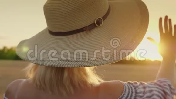 摸摸太阳的手一个戴着宽帽子的女人把手伸向太阳向后看视频的预览图