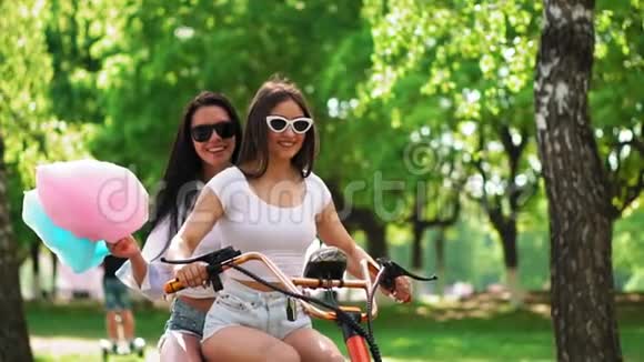 穿着短短裤穿着甜棉的女孩在公园里骑电动滑板车视频的预览图