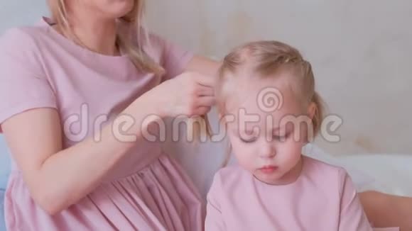 妈妈在用毛毡笔画画的时候把头发扎成辫子送给穿着粉红色连衣裙的迷人的小女儿视频的预览图