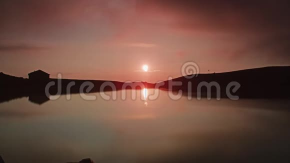 一个名为山眼的湖上日出的时间推移形成了一片粉红色的天空视频的预览图
