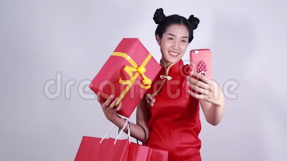 女人穿旗袍用手机自拍带购物袋和礼物视频的预览图