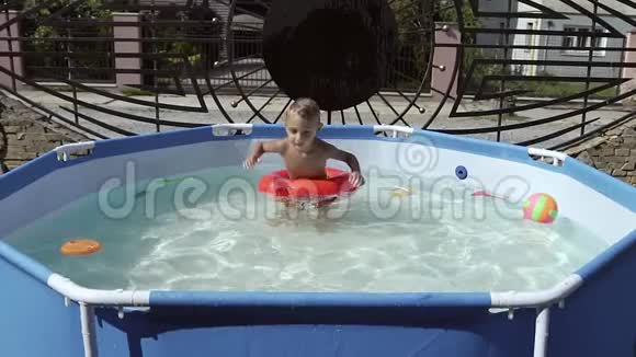 那个男孩漂浮在游泳池里的充气游泳池上视频的预览图