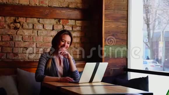 漂亮的女孩坐在咖啡馆里用笔记本电脑和男朋友聊天视频的预览图