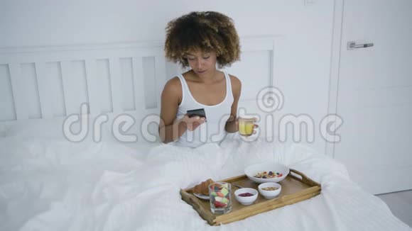 带电话的女人在床上享用早餐视频的预览图