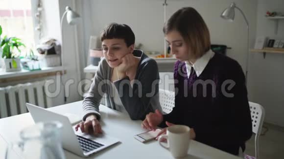 两个女朋友用笔记本坐在桌上视频的预览图