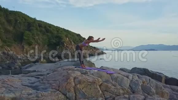 Flycam展示了女孩在黎明时分在海岸弯曲瑜伽姿势视频的预览图