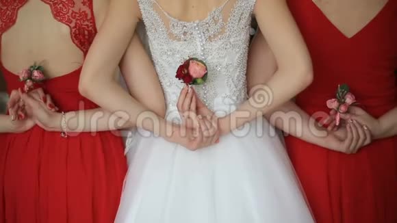 新娘和两个穿着红色裙子的伴娘的后景手里拿着可爱的粉红色玫瑰没有脸婚礼视频的预览图